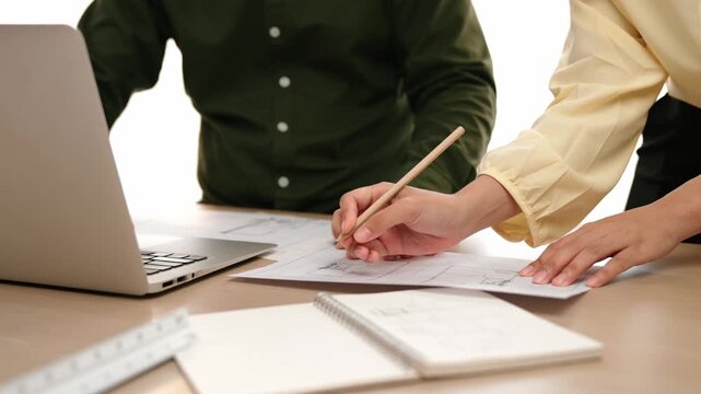 Architect and engineer compare hand writing draft with construction blueprint detail display in laptop for accurate design, measurement tool and plan on table at modern office. Closeup. Delineation.