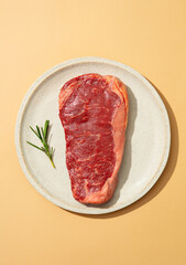 Striploin Steak with Herbs on a white plate. Beige background. Close up. Top view.