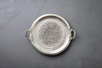 Antique silver serving tray featuring detailed floral design and decorative handles. Grey background. Copy space. Top view.
