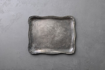 Elegant silver tray with ornate edges on textured gray background. Copy space. Top view.