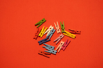Miniature wooden clothespins arranged on a bright red background. The small clips are neatly placed, creating a playful and creative composition