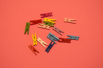 Miniature wooden clothespins arranged on a bright pink background. The small clips are neatly placed, creating a playful and creative composition