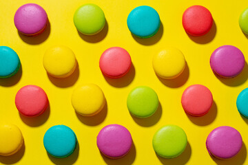 Colorful macarons dessert collection on bright yellow background. Top view.