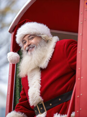 Photorealistic Santa Claus smiling joyfully from festive red holiday sleigh, spreading cheer and warmth during season