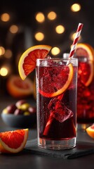 Blood orange cocktail with ice and a striped straw. Vertical photo of a refreshing red sangria drink against a dark background with festive bokeh lights