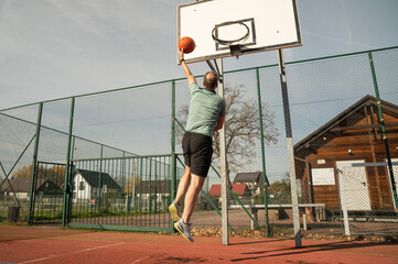 osoba rzuca, bawi się piłką do koszykówki na boisku na zewnątrz w słoneczny dzień © siwyk
