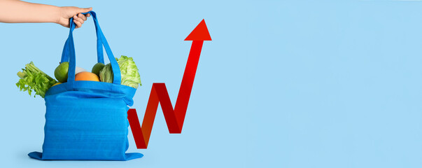 Female hand with vegetables and fruits in cloth bag on blue background