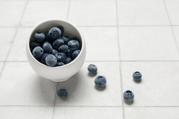 Bowl of frozen blueberry on white tile background