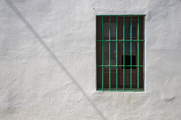Weathered white wall with green security grille in Aljarafe, Spain