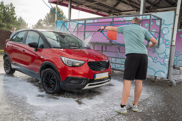 mężczyzna myjący samochód na myjni samoobsługowej