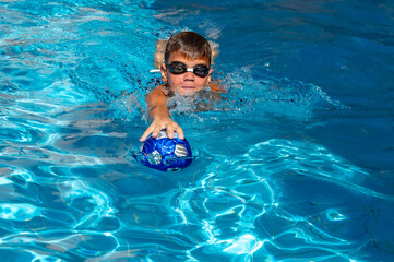 young athletic boy playing ball in the pool