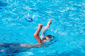 young athletic boy playing ball in the pool