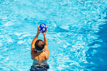 young athletic boy playing ball in the pool