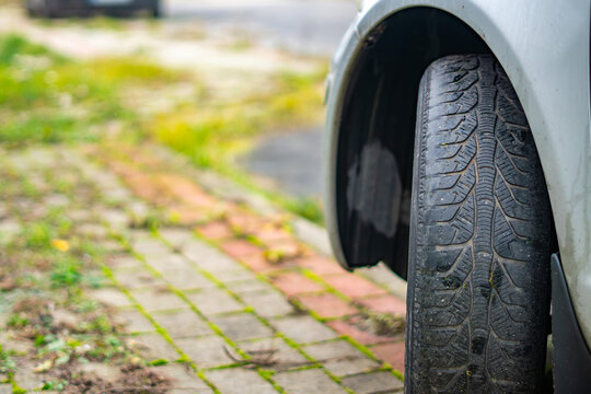 Worn car tire in poor technical condition with visible tread wear and uneven surface, automotive, road safety issue.