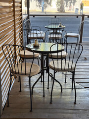 Small cafe terrace with chairs and tables by the street. Social interaction, hospitality, and calm urban lifestyle in open-air seating area.
