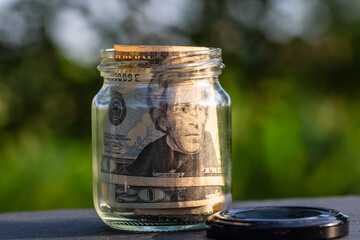US dollar banknote saving money in glass jar. Consumption and economy