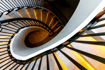 View of a mesmerizing spiral staircase with radiant golden light cascading down each step, a modern architectural marvel, Pathum Wan, Krung Thep Maha Nakhon, Thailand.