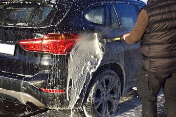 A man washing a car at a self-service car wash