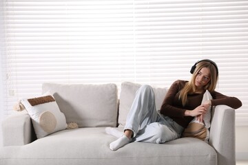 Obraz premium Depressed teenage girl in headphones on sofa at home