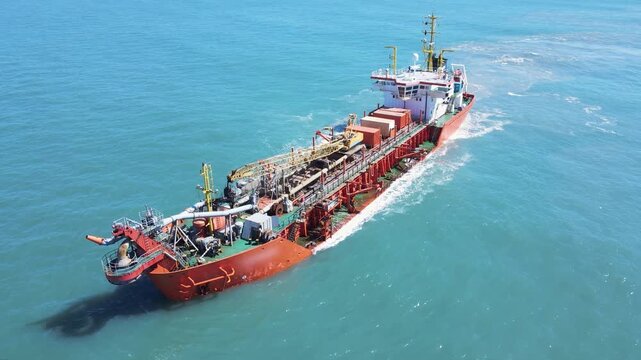 Aerial view of a dredging vessel operating offshore, showing the ship during maritime operation, suction dredger on the coast widening the sand strip beach.