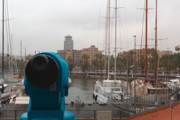 Blue coin-operated viewer overlooking marina in Barcelona