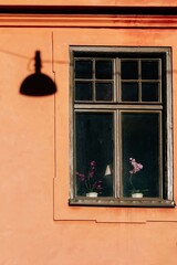 Shadow of streetlamp beside vintage window on peach facade in Stockholm