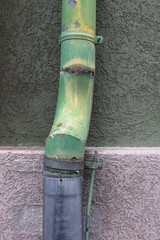 Weathered green drainpipe on textured exterior wall