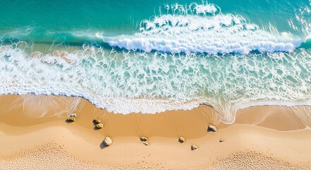 Fototapeta premium Aerial view of ocean waves crashing onto a sandy beach, creating white foam and turquoise water.