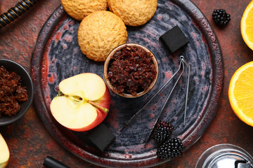Parts of hookah with tobacco, fruits, berries and cookies on red grunge background