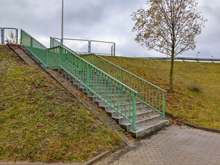Fototapeta premium Empty outdoor sports court with green metal fence and bare trees in urban recreational area Warsaw Poland autumn morning. High quality photograph.