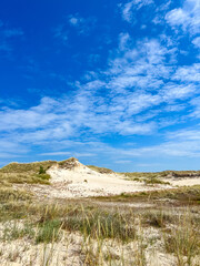 Pristine white sand dunes with green grasses under vibrant blue sky in Leba Poland Baltic Sea nature reserve. High quality photograph