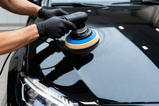 Car detailing process: polishing a black car with a professional machine