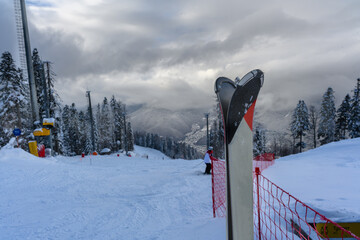 A pair of skis against the backdrop of a ski slope in the mountains