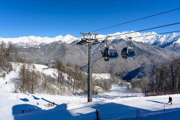Cable car cabins against snowy mountains and clear skies