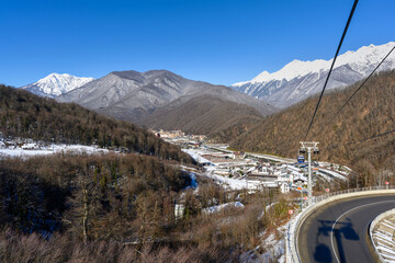 A view from a cable car descending through snow-covered trees with a mountainous landscape in the background