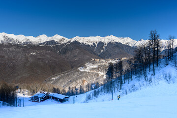 A charming mountain village surrounded by snow-covered trees and mountain slopes.