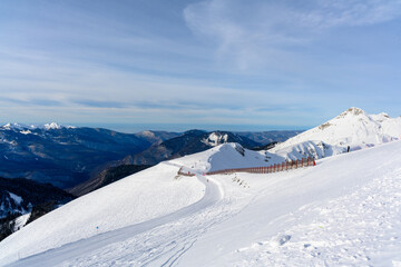 A ski slope with a protective net and the mountains.
