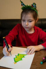 A girl draws a Christmas tree with a marker. High quality photo
