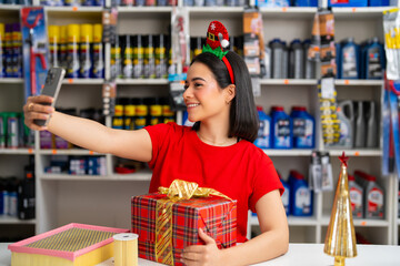 Young woman smiling, taking a christmas selfie with a gift and auto parts