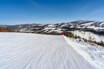 Steep ski slope with red restrictive net against the backdrop of picturesque Ural Mountains landscape.