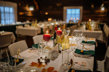 Elegant dining setup featuring beautifully arranged tables with candles, wine bottles, and seasonal decorations, creating a warm and inviting atmosphere for a festive gathering