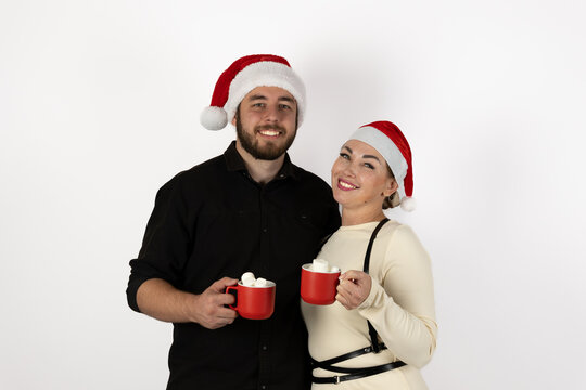 The couple is enjoying hot cocoa while wearing Santa hats for the Christmas