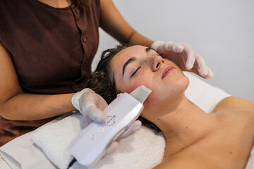 Woman receiving ultrasonic facial skincare treatment at spa