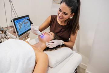 Woman receiving facial light therapy treatment at beauty clinic