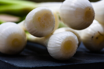 Close up of details of fresh green onions (scallion) on a cutting board isolated.