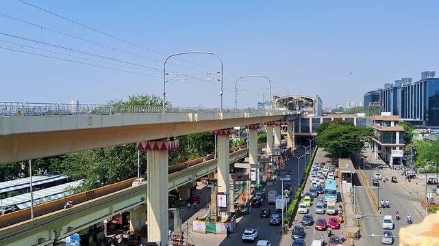 Elevated metro rail bridge above busy city road with modern buildings and vehicles during daytime