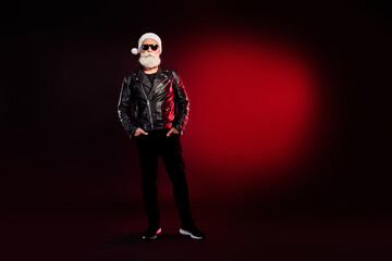 Stylish santa rocker in leather jacket with white beard and sunglass under red spotlight for...