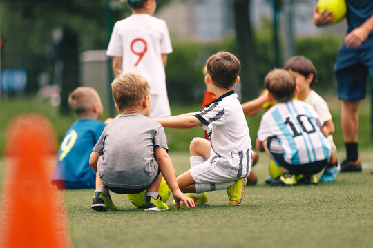 Kids Soccer Training – Young Children Sitting on Field During Football Practice. Youth Team Sports, Learning and Teamwork - Powered by Adobe
