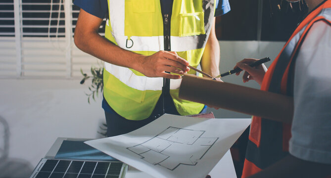 Closeup of team of industrial engineers meeting analyze machinery blueprints consult project on table in manufacturing factory. Working in manufacturing plant or production plant.