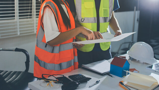Closeup of team of industrial engineers meeting analyze machinery blueprints consult project on table in manufacturing factory. Working in manufacturing plant or production plant.